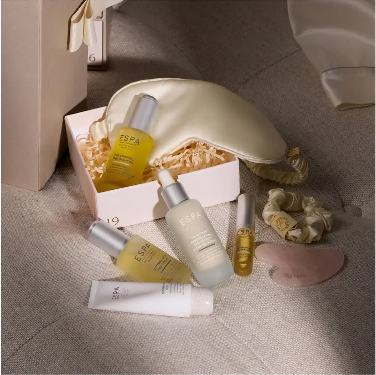 Facial oils, sleeping serum, lip treatment, balm, silk eye mask, scrunchie and gua sha around open drawer 19