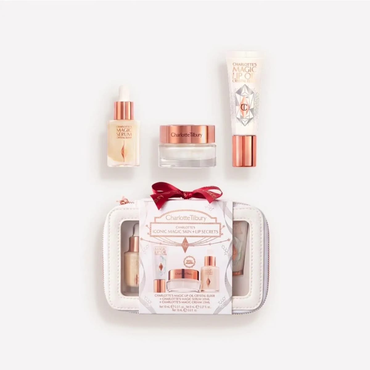 Iconic Magic Skin + Lip Secrets: Magic Serum, cream jar and Magic Lip Oil above a white zip case with red bow