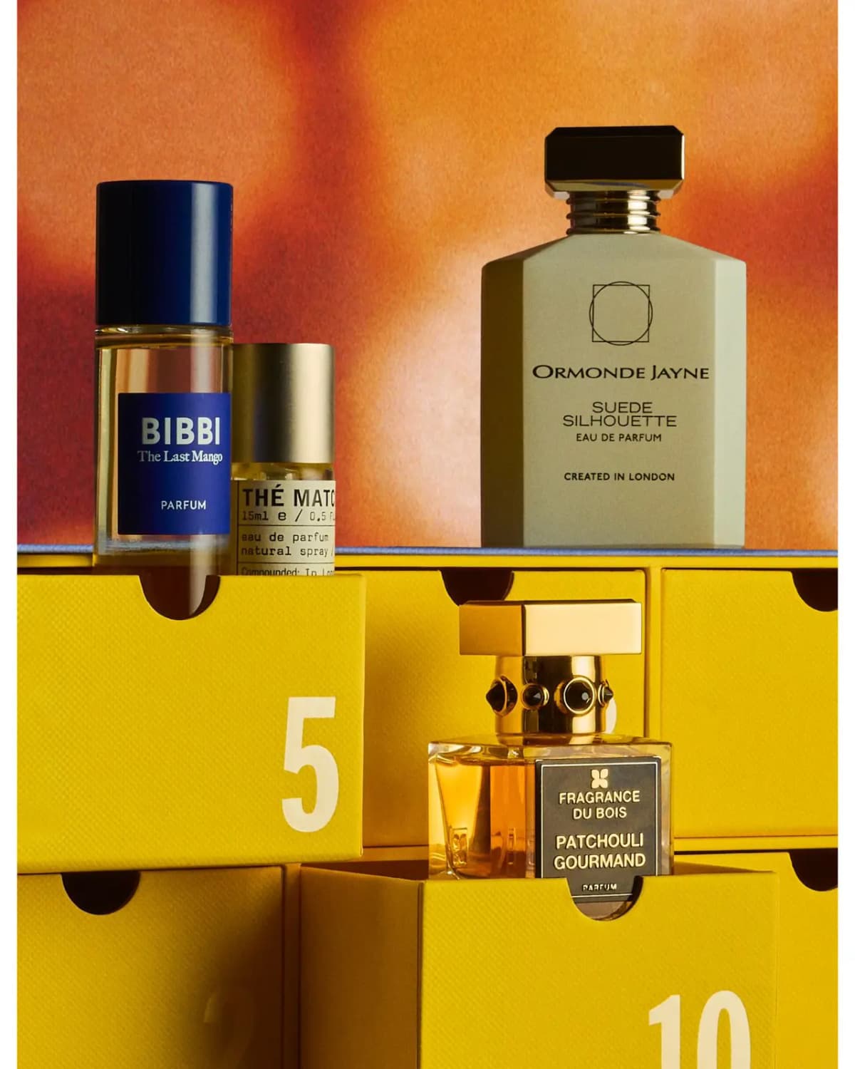 Bibbi, Le Labo and Ormonde Jayne Suede Silhouette on yellow drawers, Fragrance Du Bois below, orange backdrop