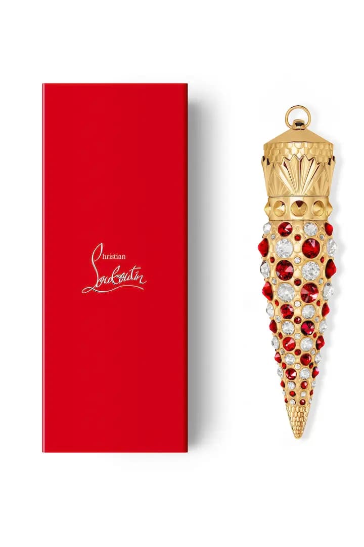Capped crystal-studded gold lipstick case beside a red box with silver Christian Louboutin signature