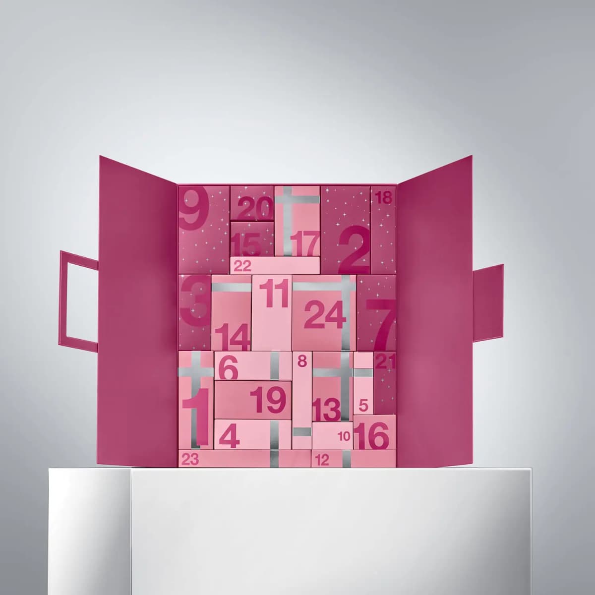 Advent calendar opened like doors, revealing pink numbered boxes 1 to 24, some tied with silver ribbon, on a white plinth