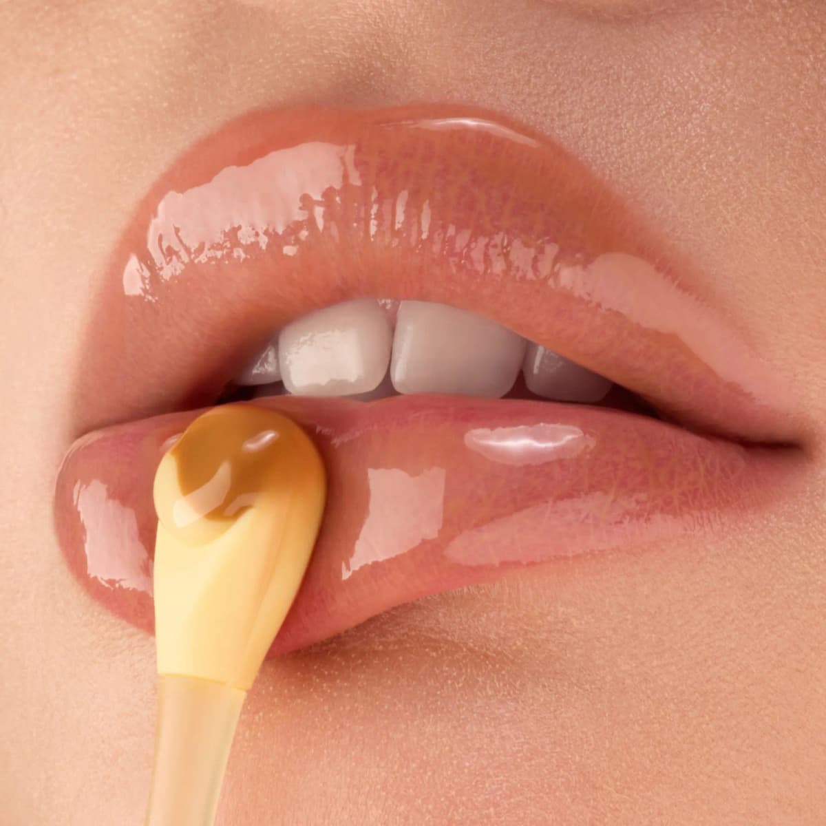 Glossy peachy lips with a spatula applying caramel and cream lip mask to the lower lip