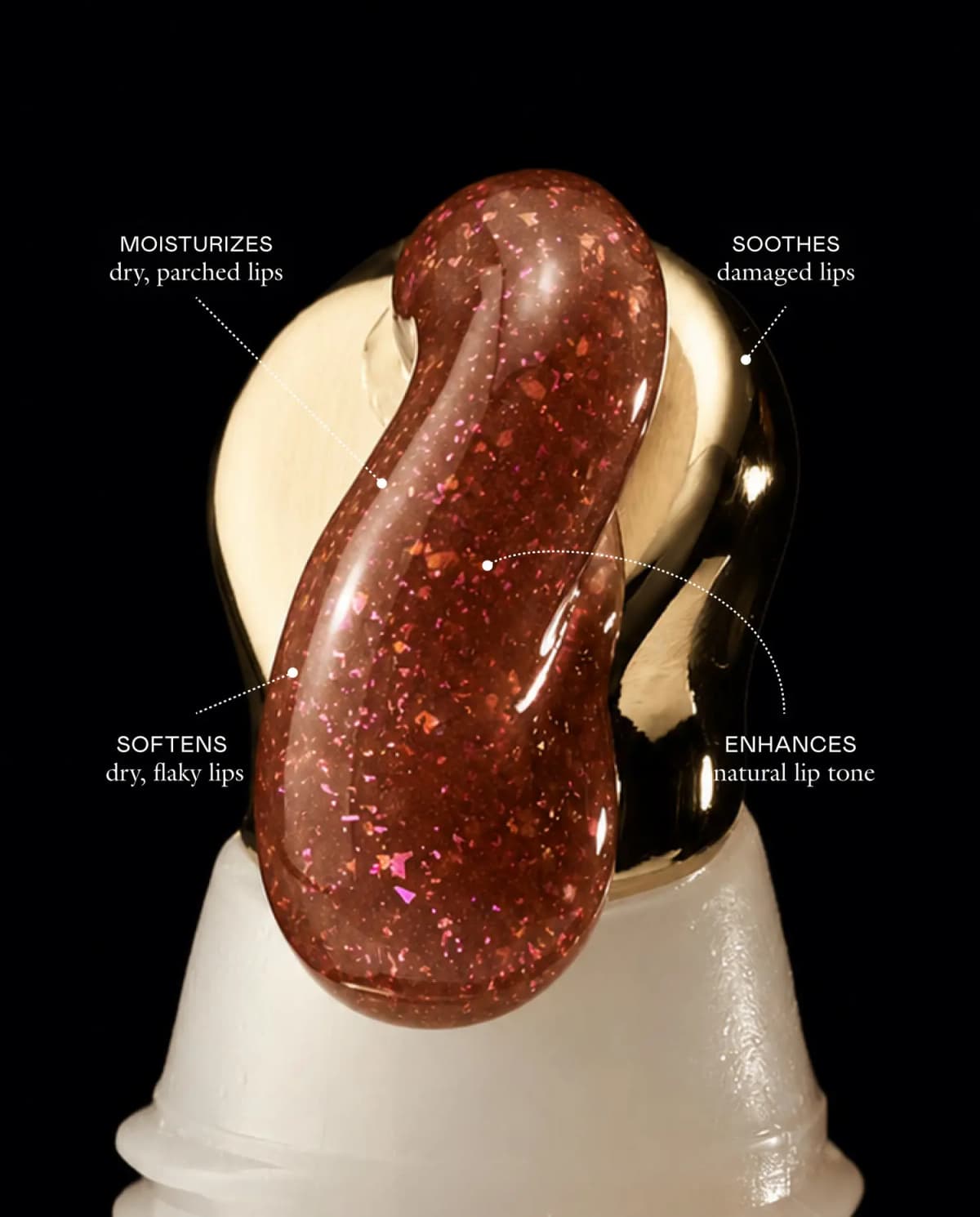 Sparkly brown balm with pink and copper flecks on a gold tube tip, labelled moisturizes, soothes, softens, enhances