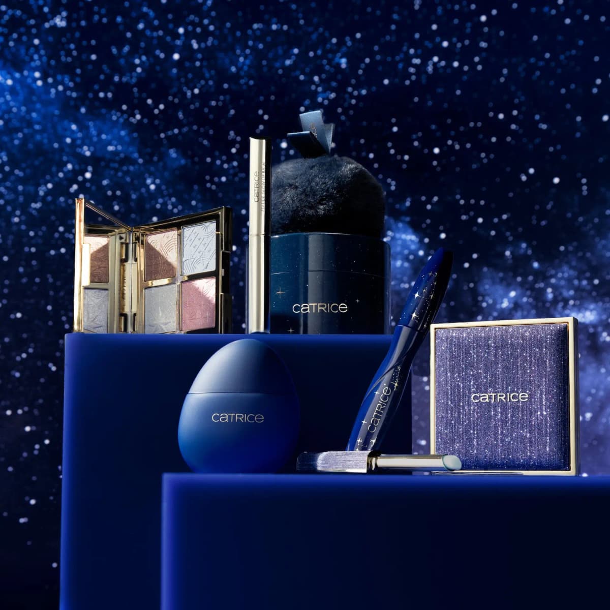 Catrice ON THE STARPATH Limited Edition palette, mascara, lip balms, highlighter and egg on blue plinths by a starry sky