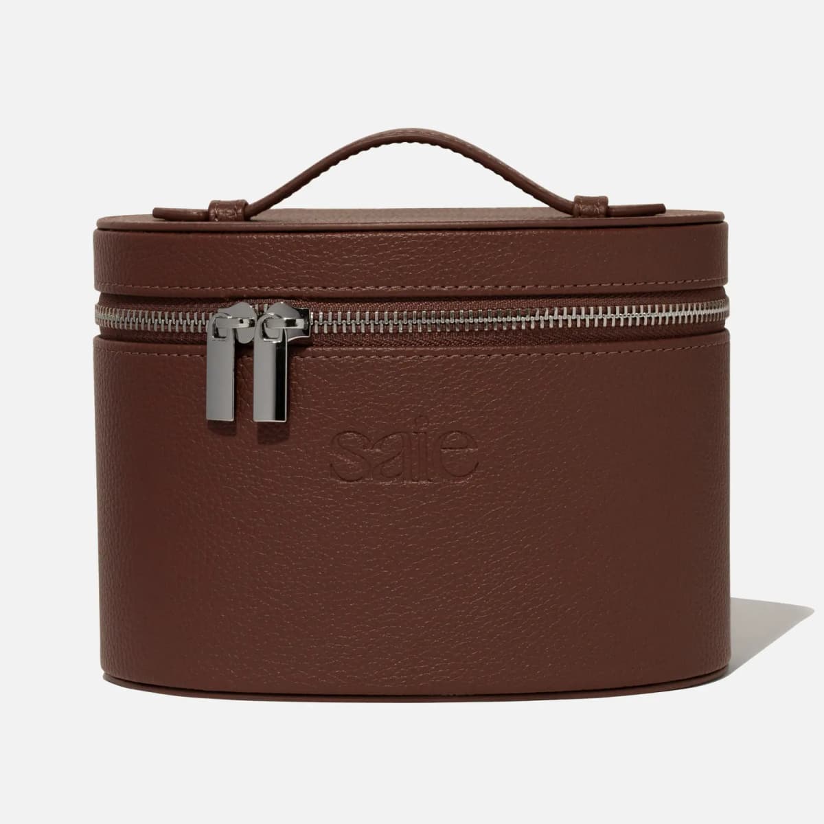 Front view of the chocolate-brown pebbled Saie Mini Vanity Case with embossed logo, silver zipper and top handle