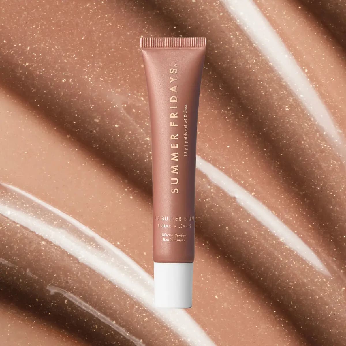 Mocha Bonbon Lip Butter Balm tube on a sparkly swirl of golden-shimmer beige balm texture