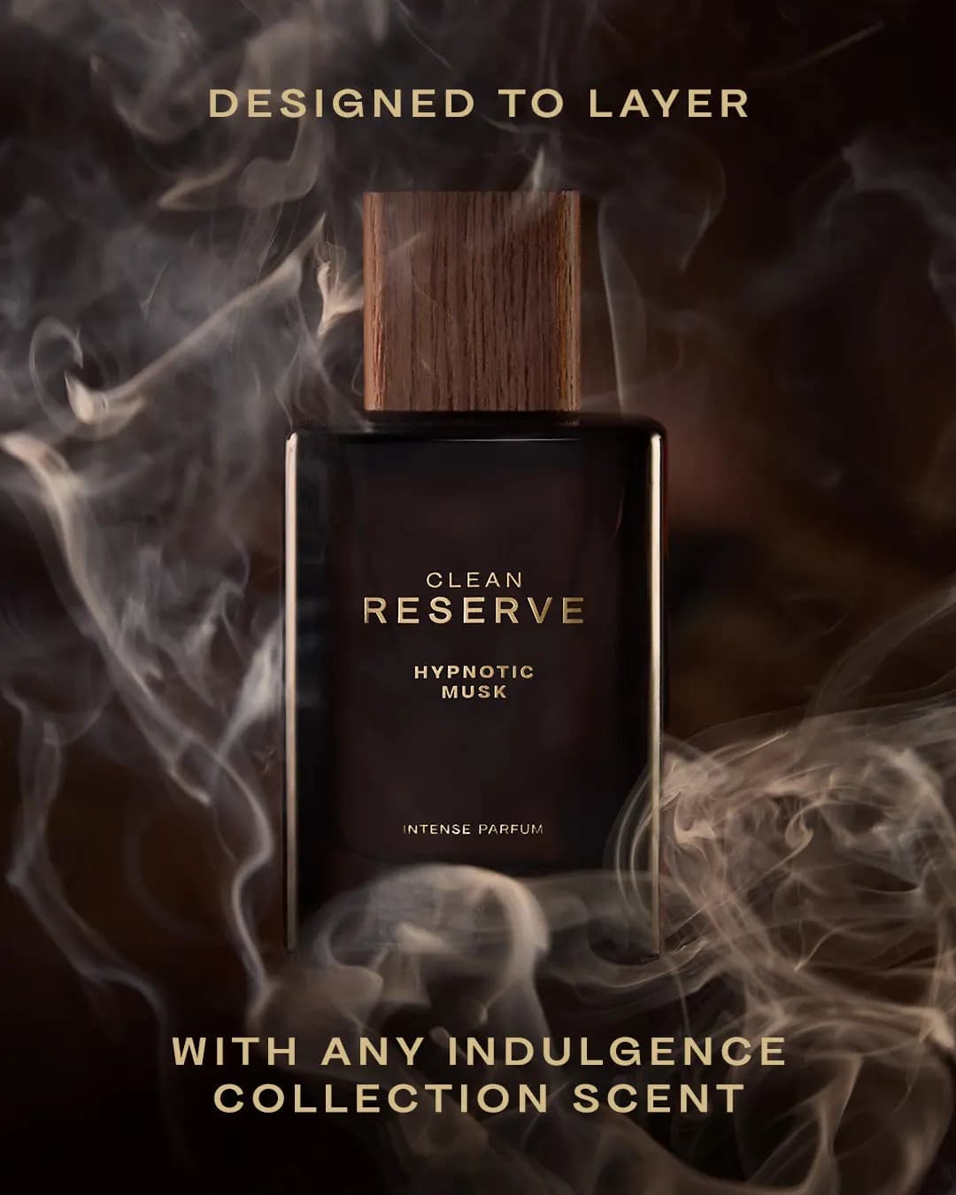 Brown Clean Reserve Hypnotic Musk bottle surrounded by swirling smoke with gold text about layering scents.