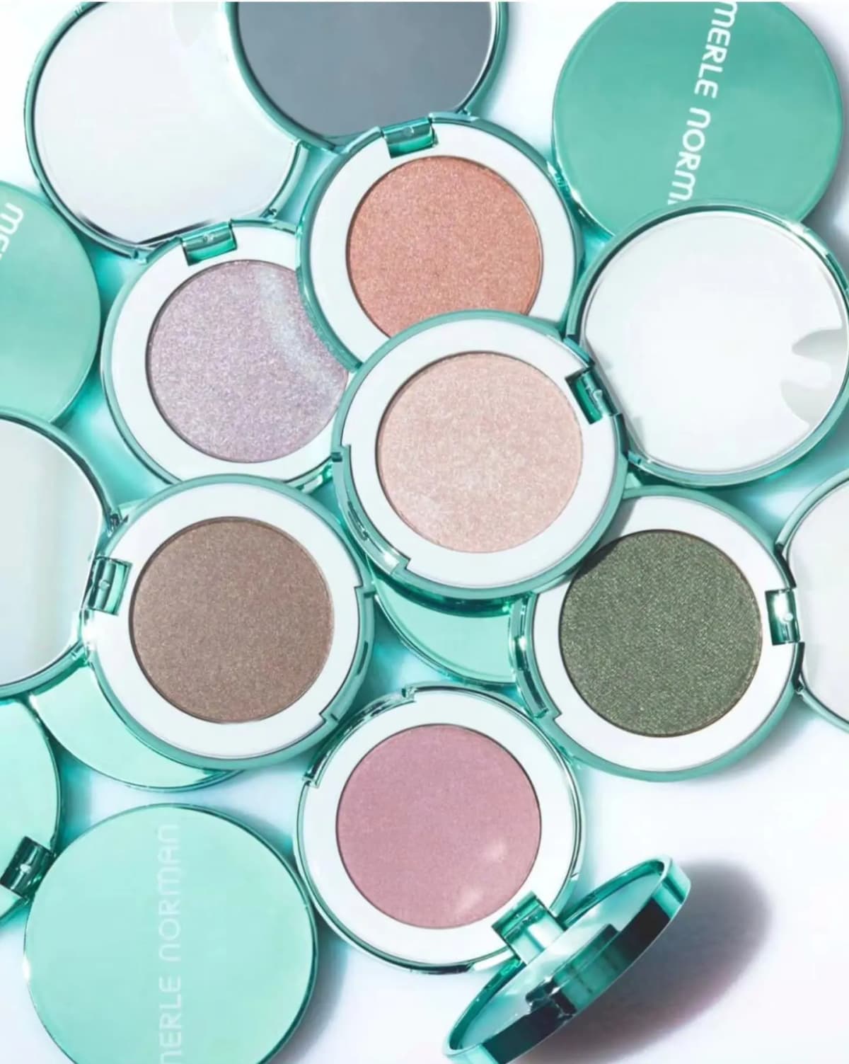 Open mint compacts showing lilac, peach, pale pink, taupe, olive green and rose shimmer eye shadows