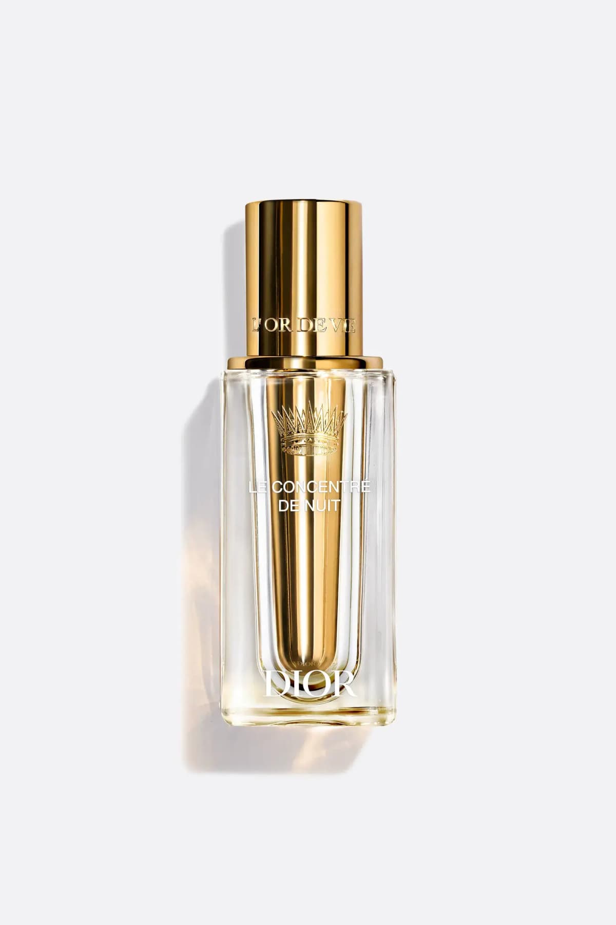 Clear square glass bottle with gold crown-etched inner vial and gold L'Or de Vie cap on a pale grey background