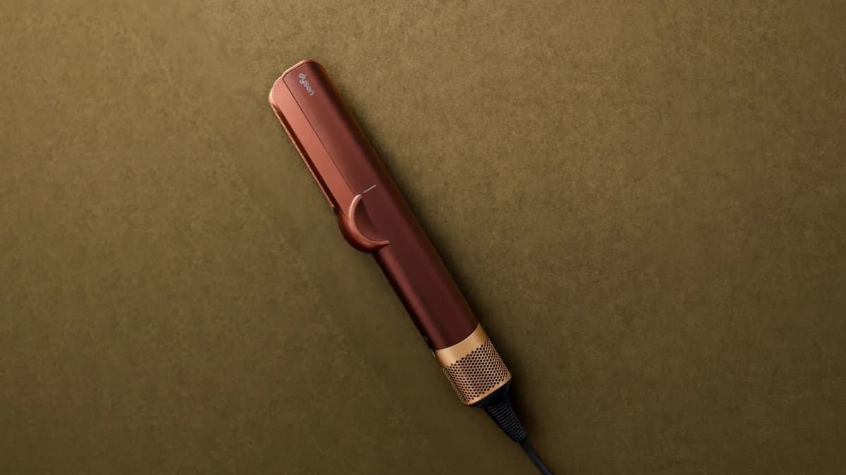 Copper hair straightener with brass vented base lying on an olive suede surface