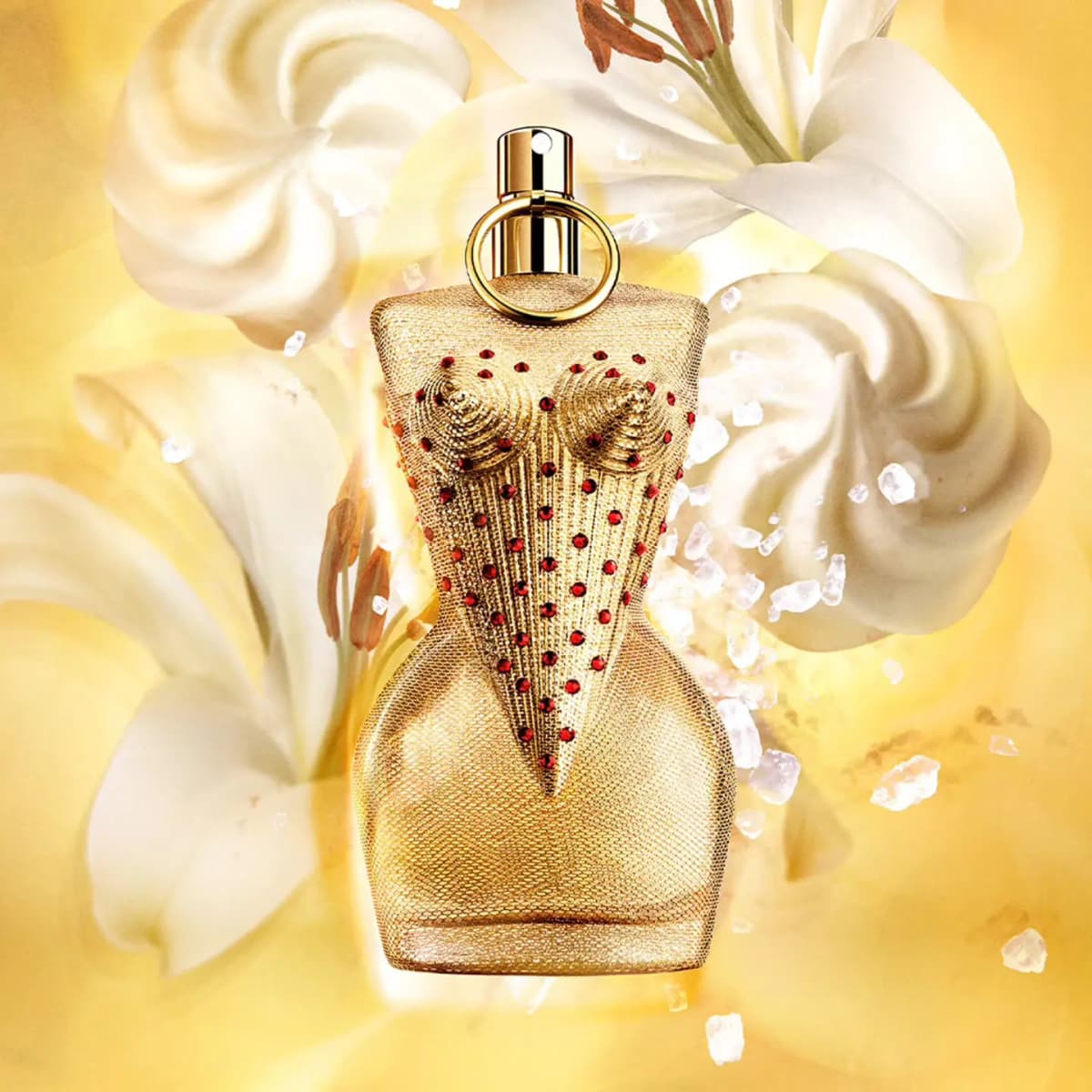 Gaultier Divine Collector Edition Eau de Parfum bottle in gold mesh with red crystals among white lilies and meringue swirls