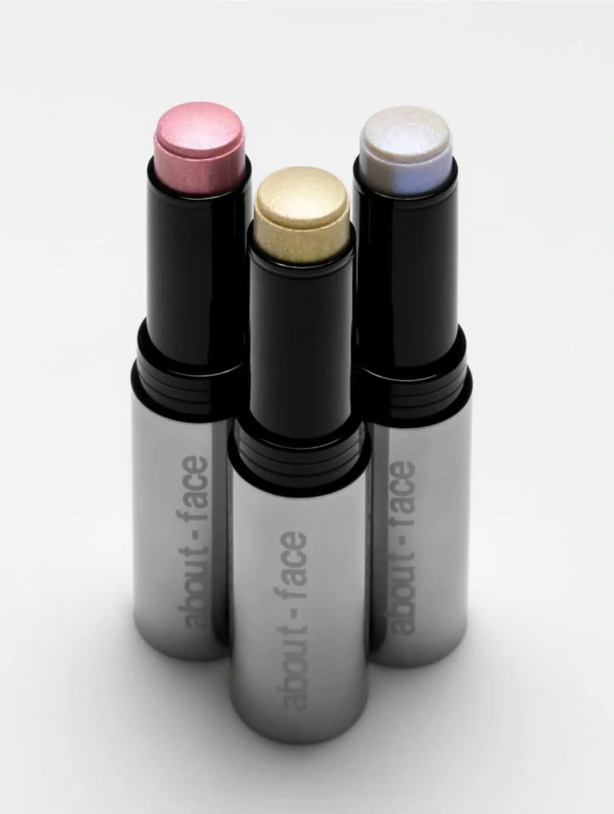 Three about-face Cooling Chromes highlighter sticks in pink, pale gold and iridescent lilac with silver tubes