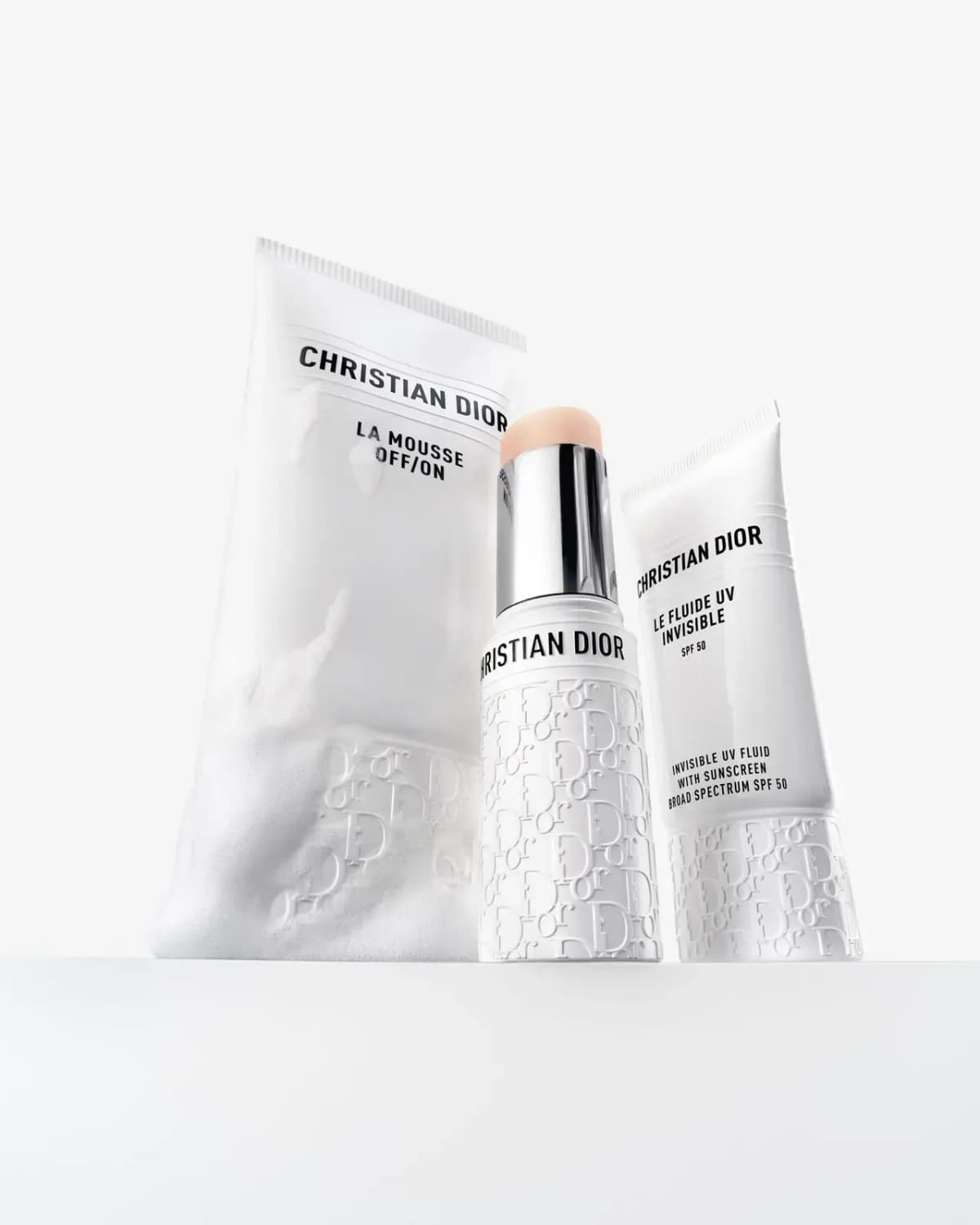 Stick between La Mousse Off/On cleanser tube and Le Fluide UV Invisible SPF 50 tube on a white backdrop