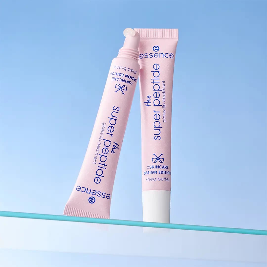 Two pink super peptide lip tubes leaning on a glass shelf, one uncapped with clear gloss at the tip