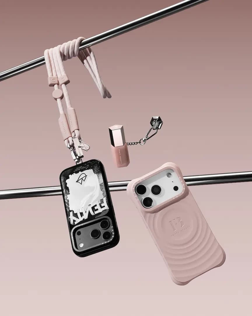Black graffiti mirror case on a pink rope strap and a pink ripple case hang from chrome bars beside a lip gloss charm