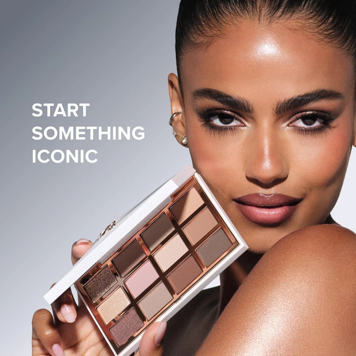 Model with sleek hair holding open neutral eyeshadow palette beside her face, text reads Start Something Iconic.