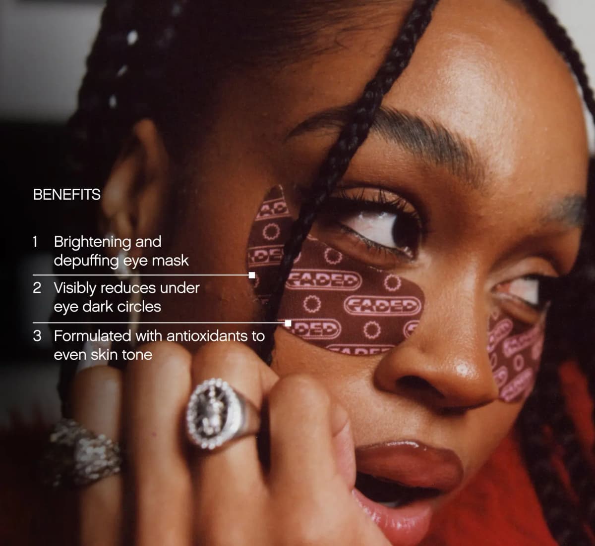 Close-up of a model with braids wearing brown Faded under-eye masks beside brightening and depuffing benefits